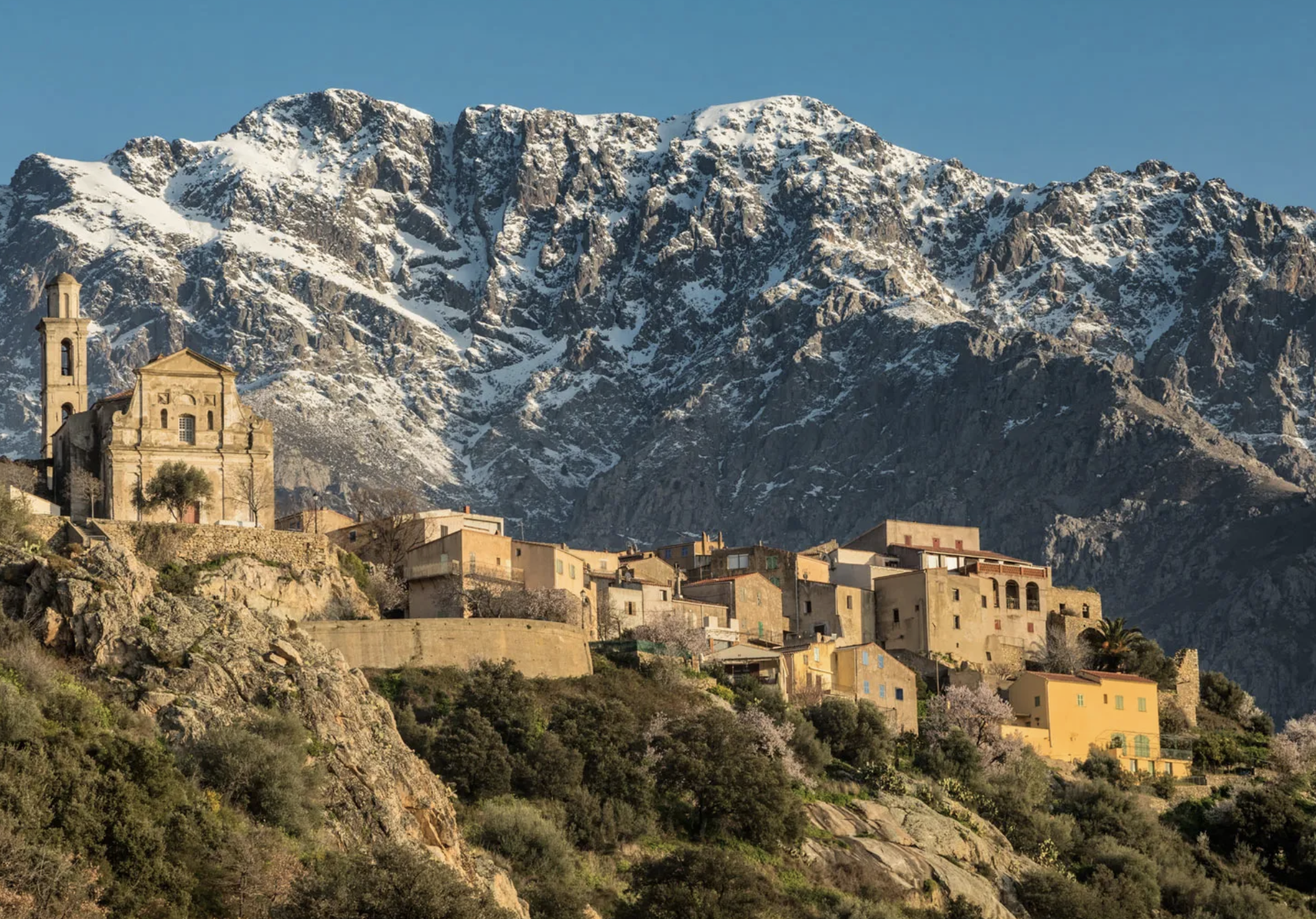 A mountain village in Corsica's interior, backed by snow-capped peaks