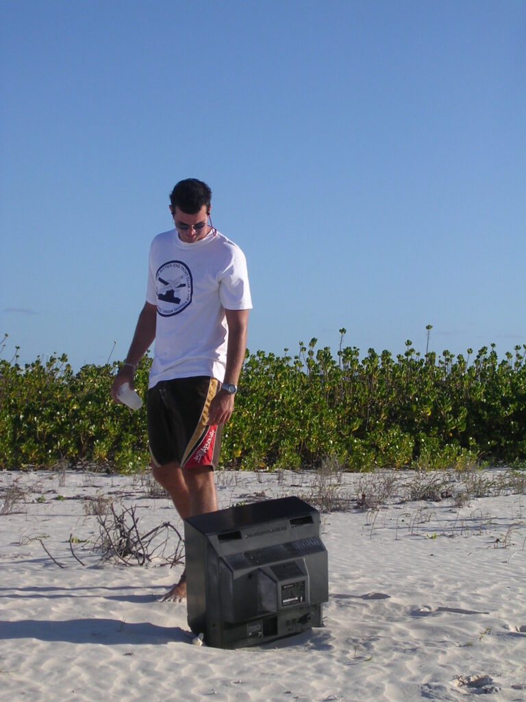 Garry standing beside an old television abandoned on a beach in the British Virgin Islands