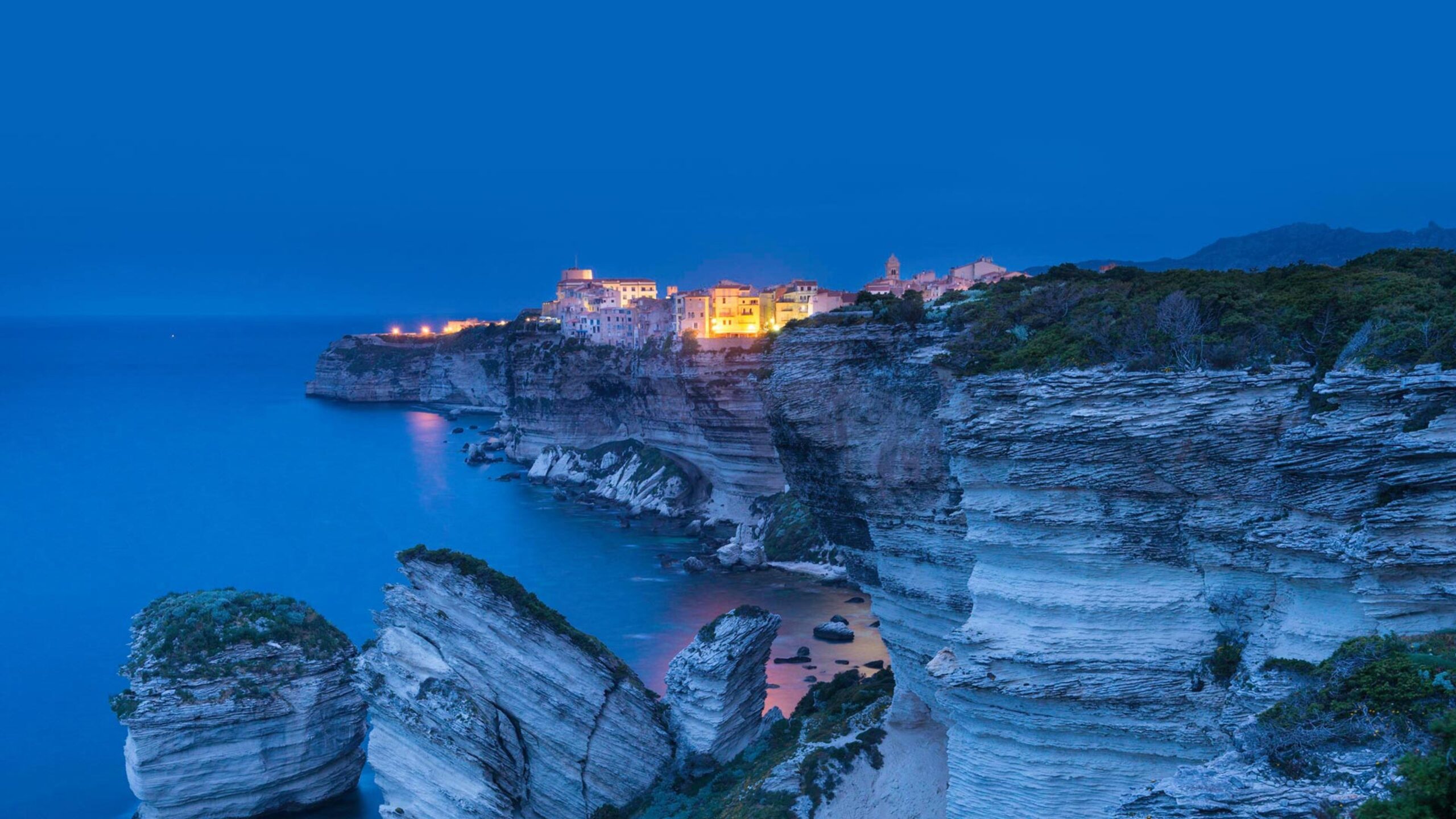 Bonifacio's citadel lit up at dusk above its limestone cliffs, Corsica