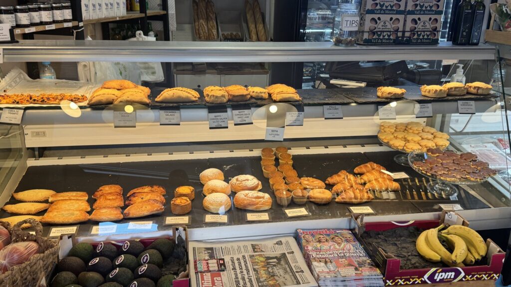 The pastry case at Cafeteria Capritxo, filled with cocarrois, ensaimadas, and carrot muffins
