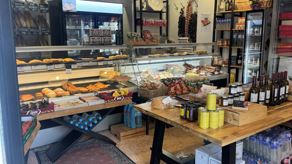 Inside Cafeteria Capritxo, shelves of local wine, bread, and groceries around the counter