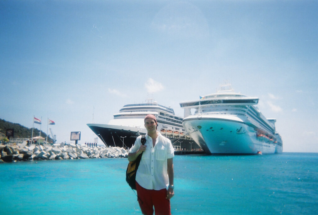 Garry standing dockside with a backpack in front of two cruise ships in Sint Maarten