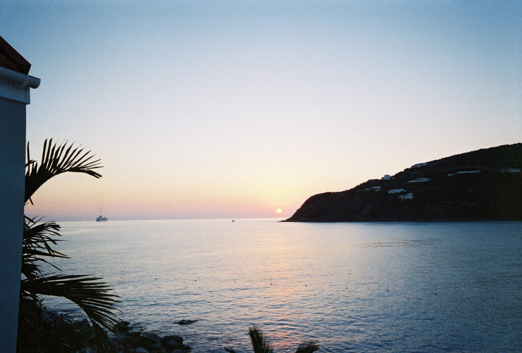 Sunset silhouette of a hillside with a cruise ship passing on the horizon